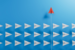 paper airplanes on blue background with red paper airplane moving vertically against them 