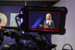 Camera screen facing a filming studio with the display screen showing Lily Haake speaking 