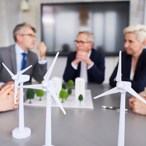 Picture of men in a meeting discussing sustainabiltlity with windmill models