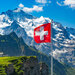 switzerland flag in the background with snowy mountains and greenery