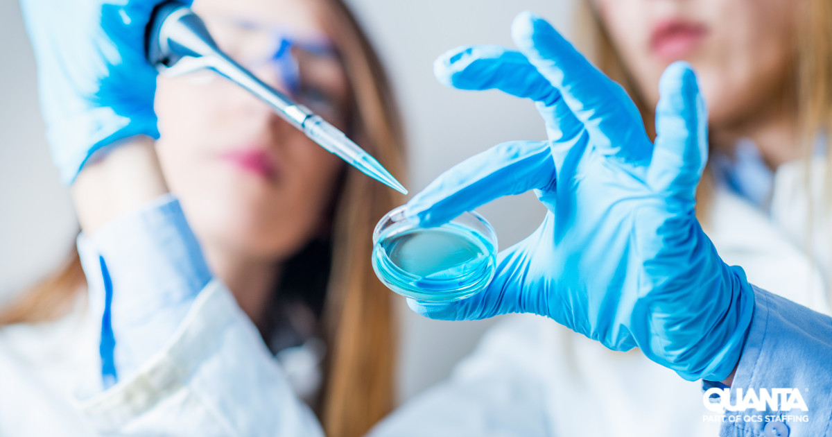 women wearing blue gloves dropping solution from a pipette into a petri dish