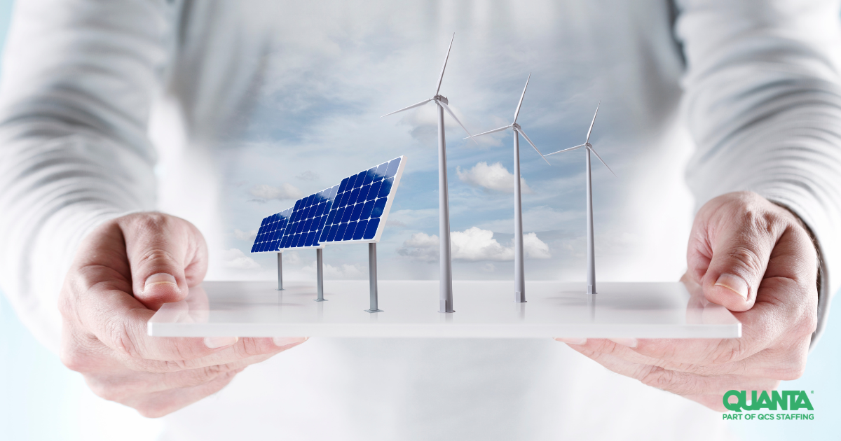 hands holding 3-d model of solar panels and wind turbines