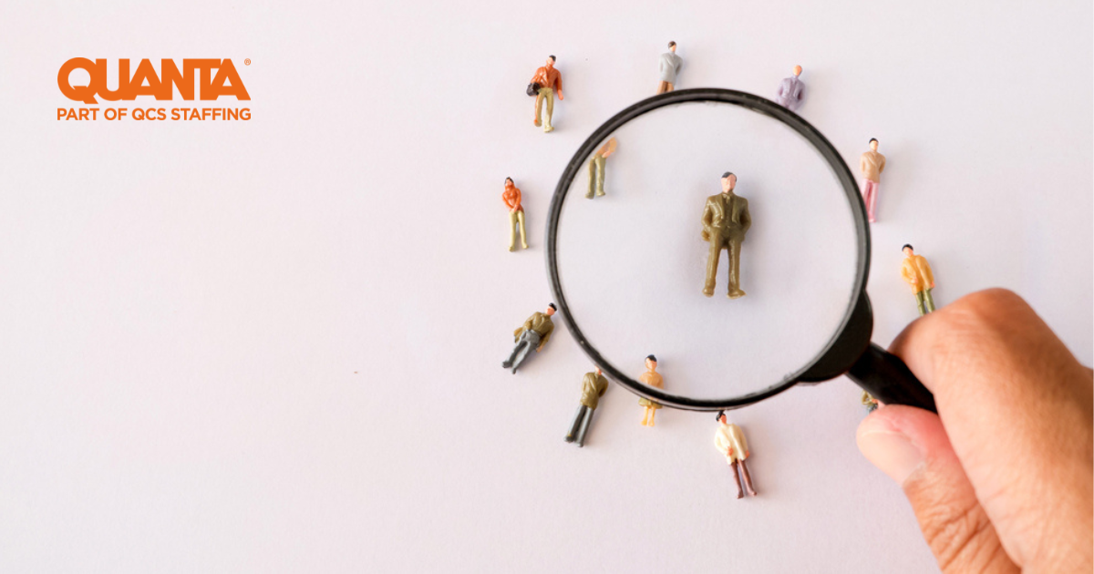 hand holding magnifying glass looking at figurines of people