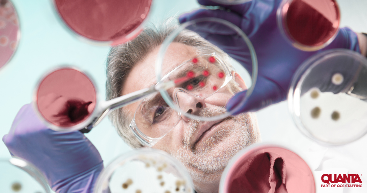 man in safety goggles and purple gloves dropping solution from a pipette into a petri dish