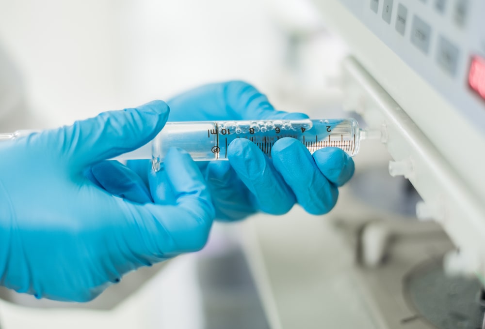 blue gloves on hands holding a syringe