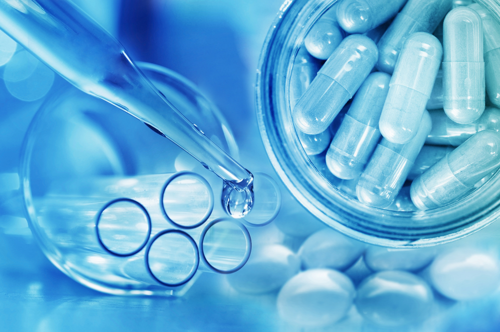 pipette dropping clear liquid beside test tubes and a container of clear capsules