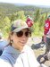 Sara smiling at the camera wearing a baseball cap in beautiful forest 