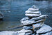 grey slates of rock piled up in the shape of an indigenous inuksuk and the sea in the background