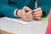 hands holding a pen with a blank piece of paper below