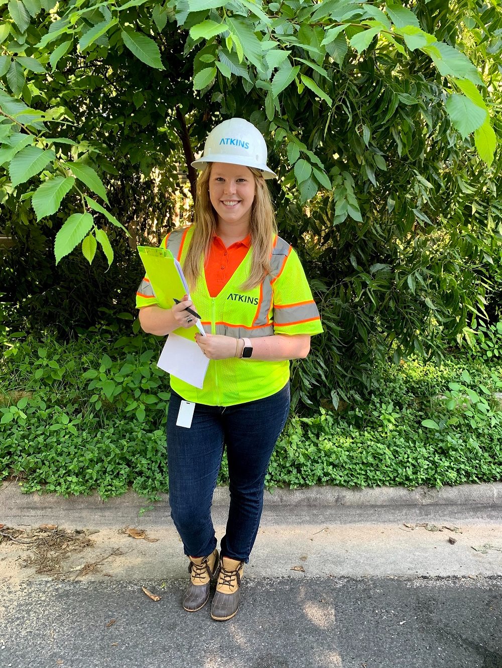 woman in high visibility vest and hard hat smiling