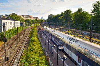 train at a station with a line of trees beside