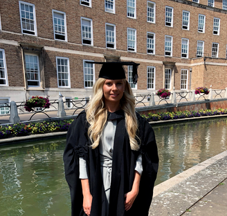 Picture of Emily smiling in graduation cap and coat