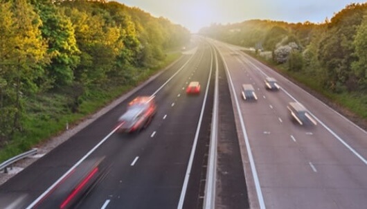 tree lined highway with blurred cars travelling along