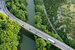 An overhead image of a busy road passing over a river with greenery on either side.