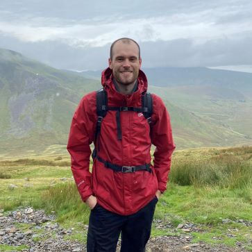 Sam Rayner smiling towards the camera on his hike