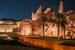 A lit up Saudi Arabian castle in the evening, with the night sky in the background and palm trees at the front