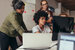 group of young professionals standing around computer