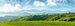 panorama of beautiful countryside of romania. sunny afternoon. wonderful springtime landscape in mountains. grassy field and rolling hills. rural scenery