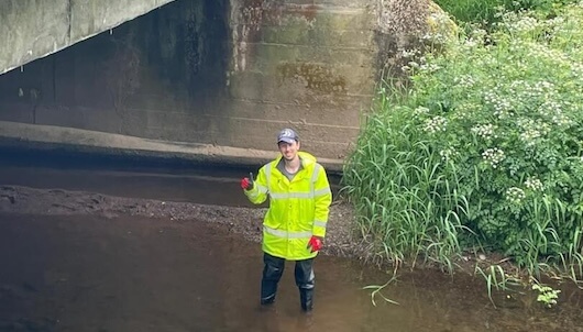 man in high visibility jacket standing under a bridge