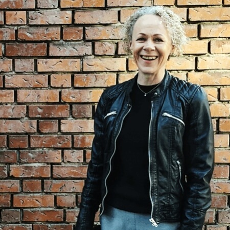woman standing by a brick wall while smiling