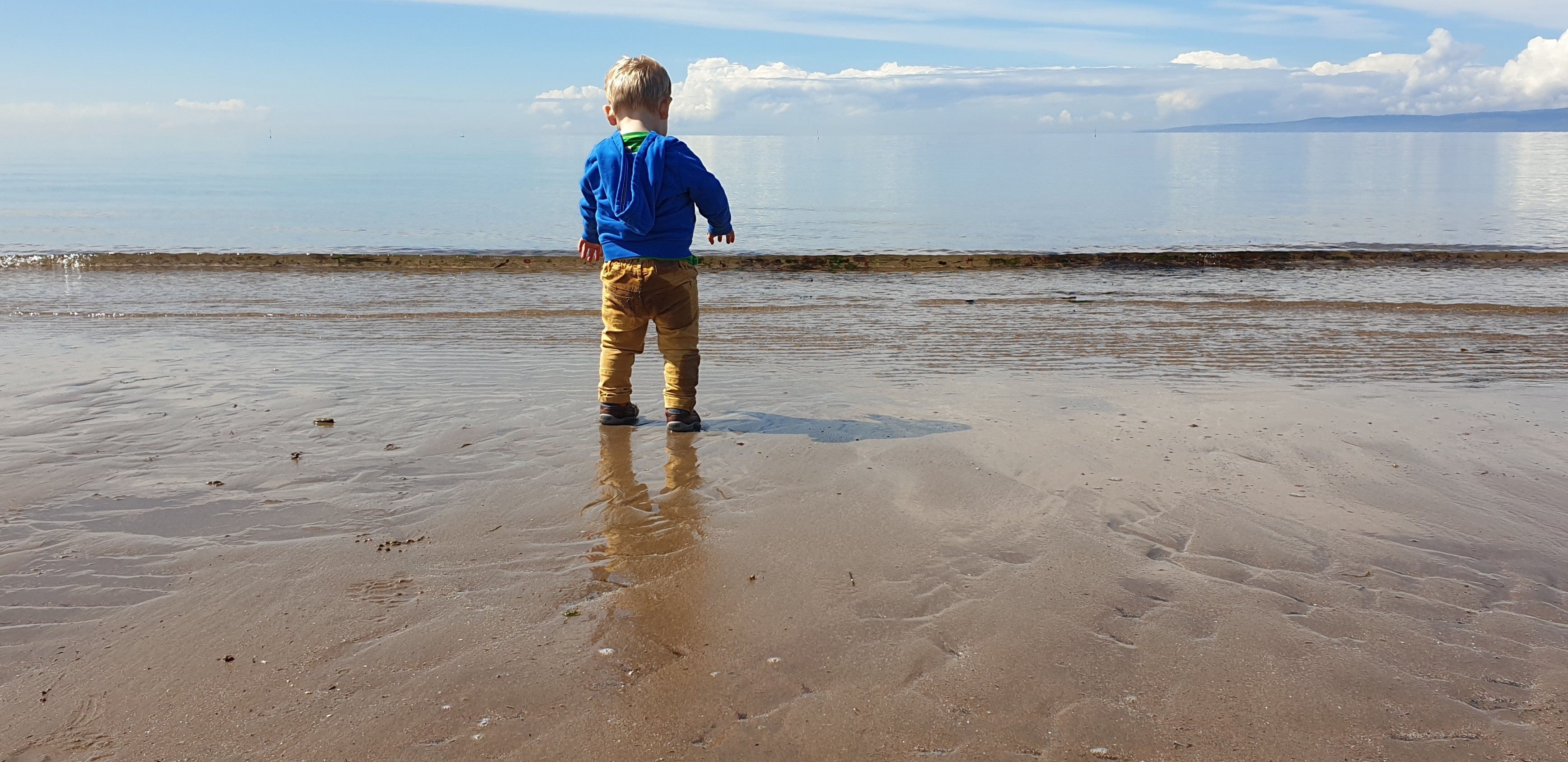 Image of a child testing the waters at a beach