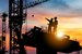 Silhouette of Engineer and worker checking project at building site background, construction site at sunset in evening time
