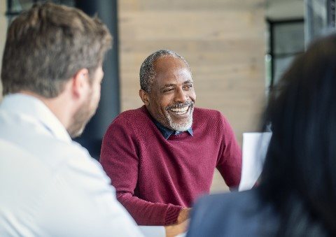 Image of a man smiling while other two people are looking at him