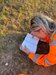 Rachel referring to a plant reference book on a grassy site 