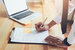 person in shirt and tie leaning over a desk writing their resume