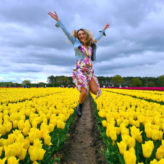 A picture of Alina jumping in a field full of yellow tulips