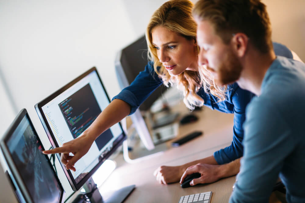 image of two colleagues looking at a desktiop reviewing designs