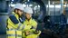 Male and Female Industrial Engineers in Hard Hats Discuss New Project while Using Laptop. 