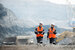 man and woman wearing high visibility jackets and hard hats walking through building site