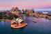 Pinkish colourful sunrise over Sydney city CBD on waterfront of Harbour around Circular quay with major architectural landmarks and symbols of Australia.