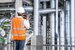 An engineer looking at a structure while wearing a hard hat and high vis jacket