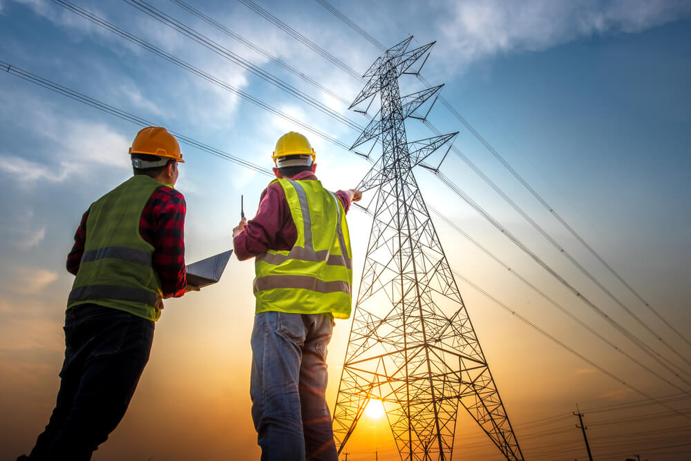 image of men in safety clothing looking at a telephone pole