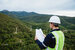 Young maintenance engineer man working with blueprint on the mountain, Environmental engineering concept.