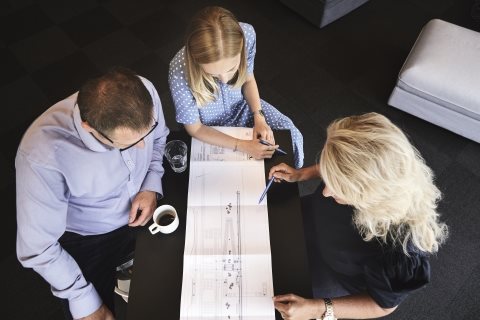 This is an image of three colleagues having a meeting looking at a blueprint