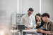 three young professionals sat around a laptop discussing