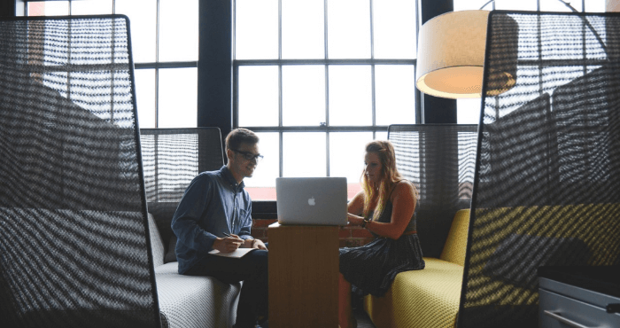 Two people in a meeting looking at their laptop