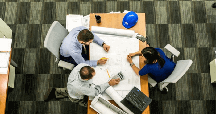 Three people sitting around a table during a meeting