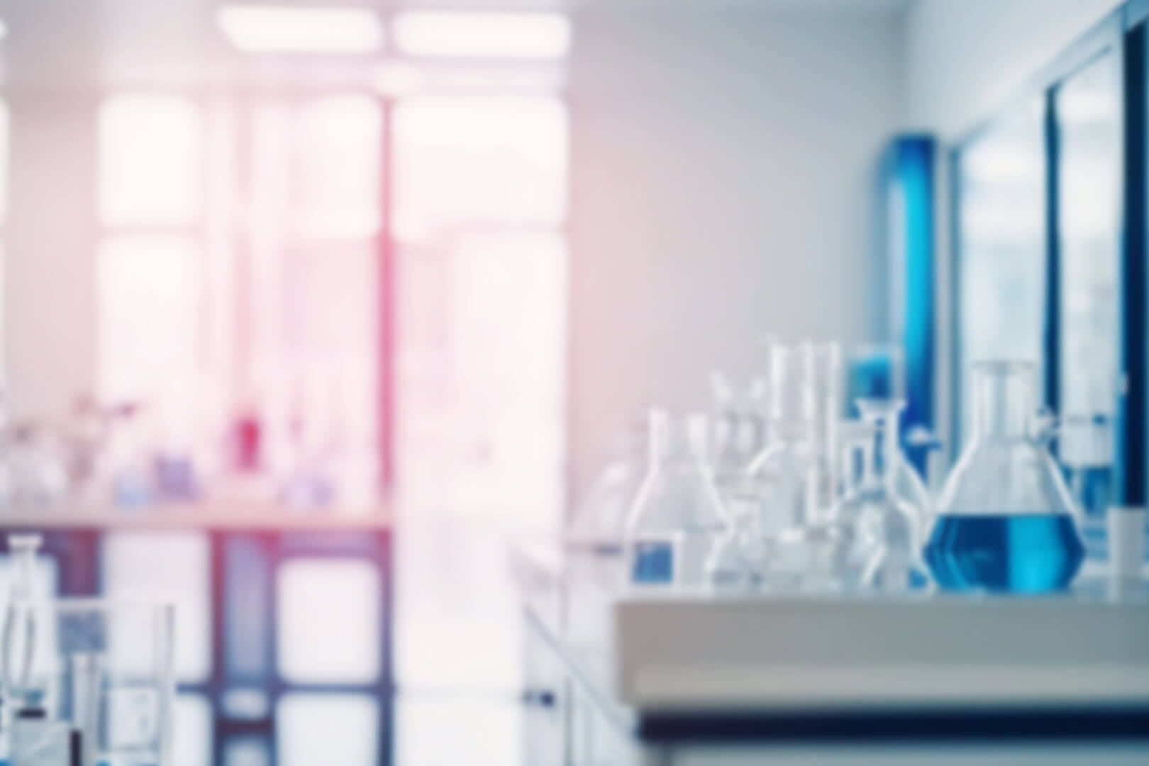 a blurred image of a laboratory with flasks full of a blue liquid