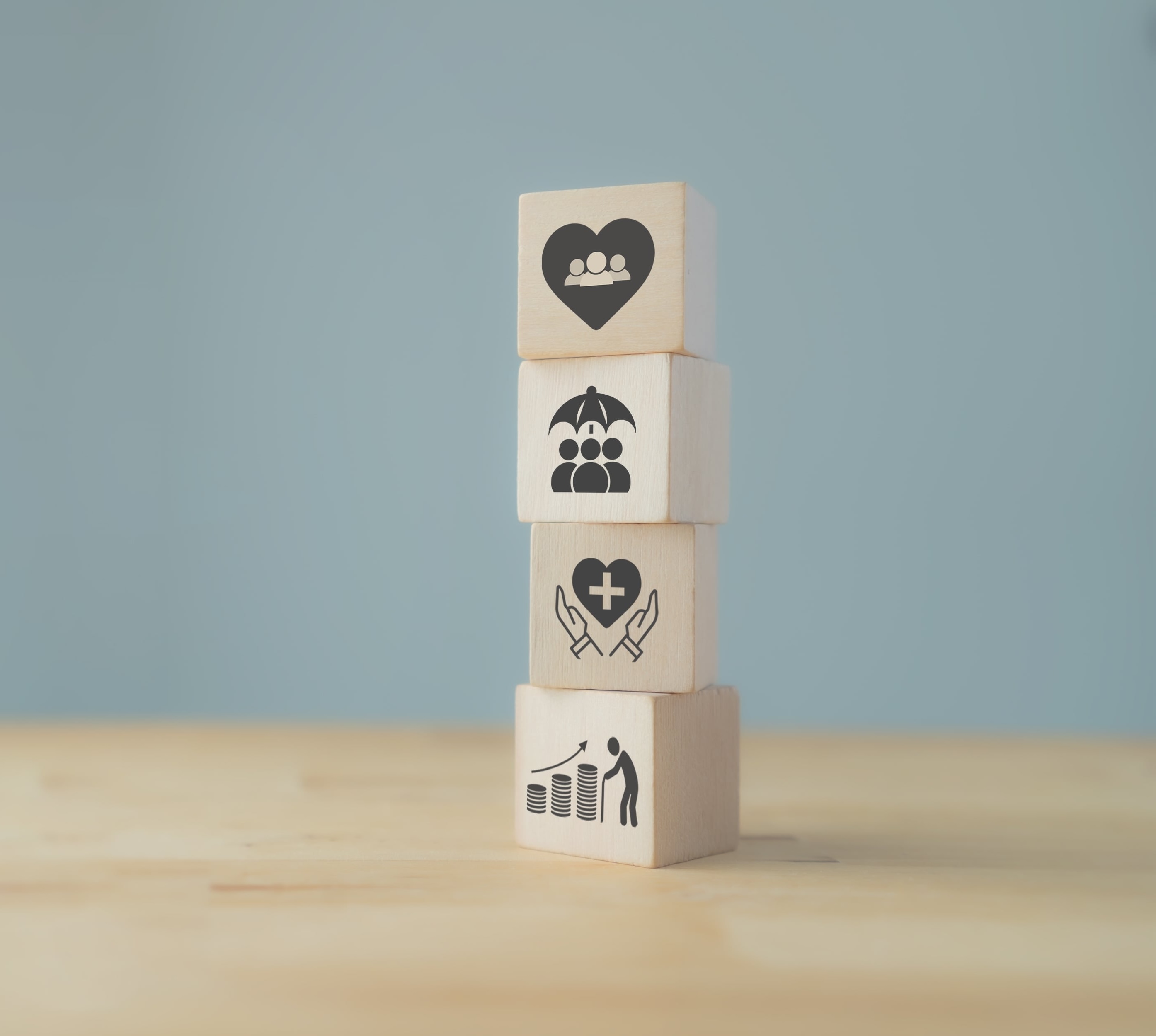 four wooden blocks stacked on top of each other each has a symbol relating to employee benefits on it.