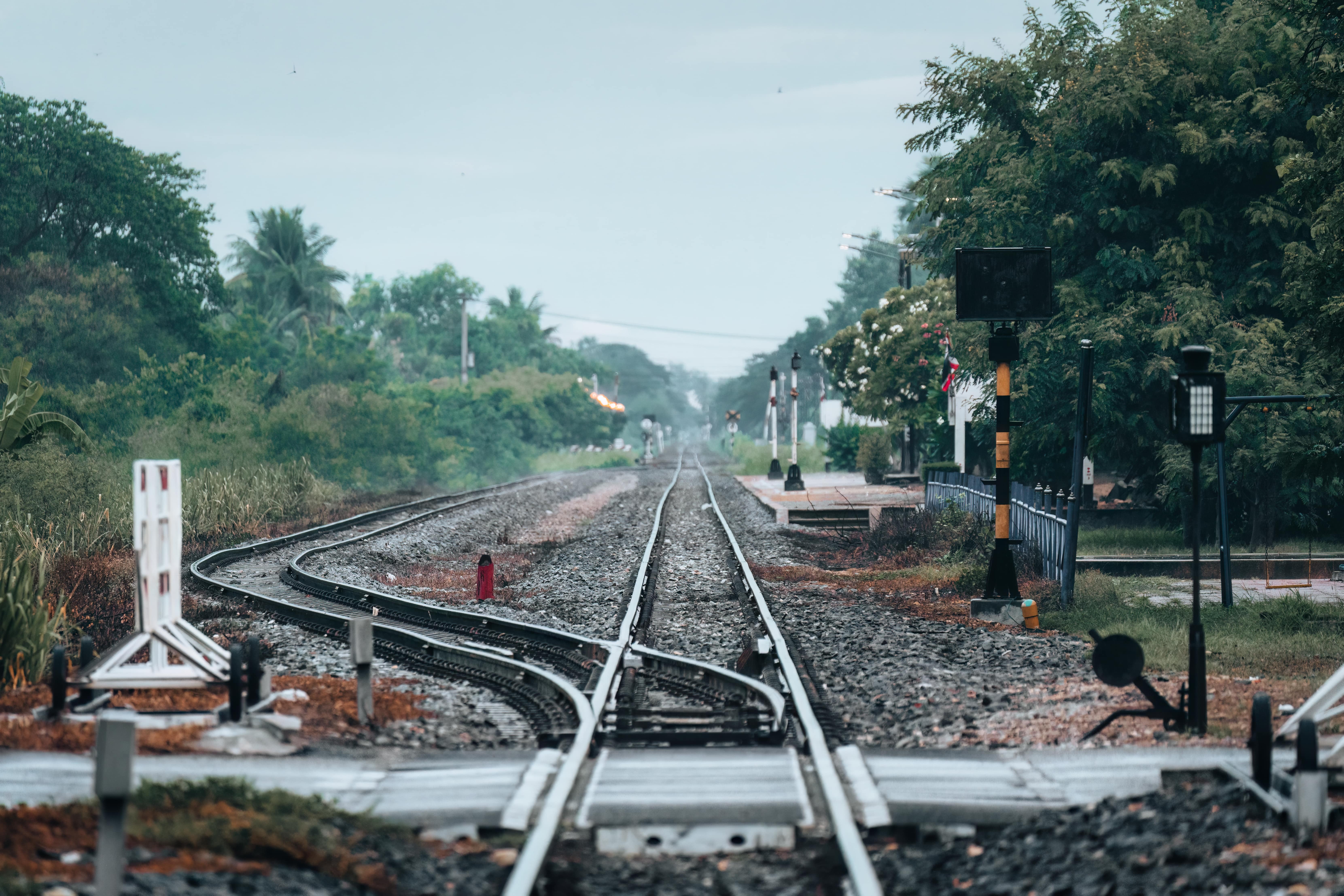 Empty train track, metal railway with rail switching and signboard pole at station in countryside