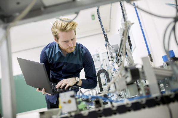 Man with laptop assessing wiring.