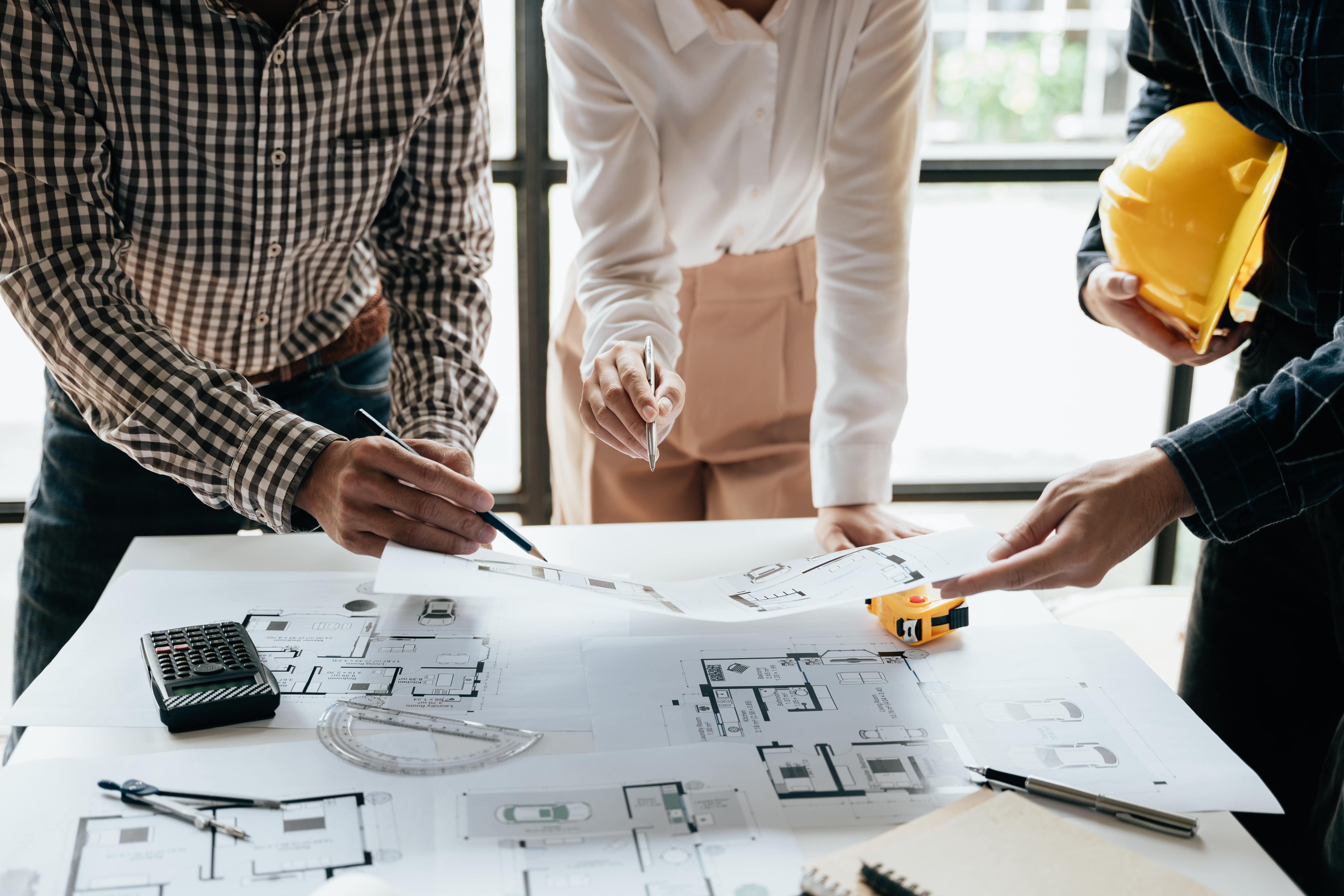 Close up of hands working brainstorming and measuring for cost estimating on paperworks and floor plan drawings about design architectural and engineering for houses and buildings.