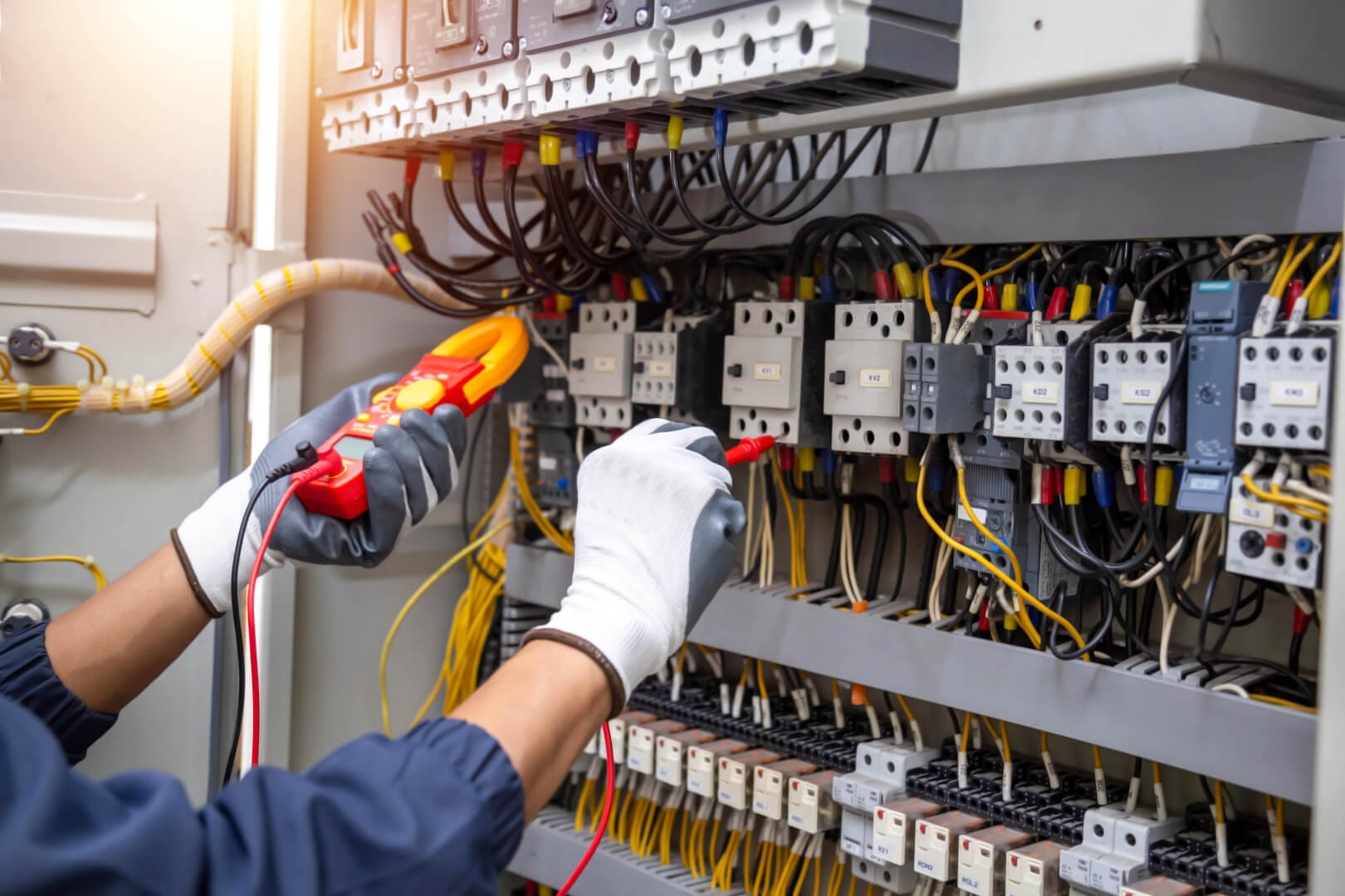 Engineer hand holding AC voltmeter checking electric current voltage at circuit breaker terminal and cable . 