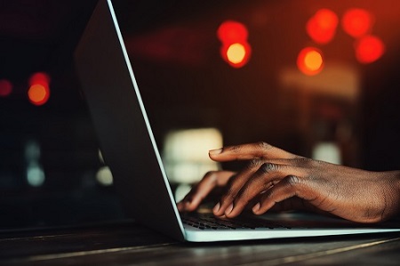 hands typing at a laptop from side on.