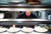 male chef looking down and standing behind four plates