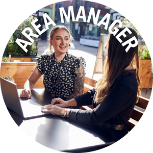 Area manager sits with colleague at outside table. Link to Area Manager Jobs